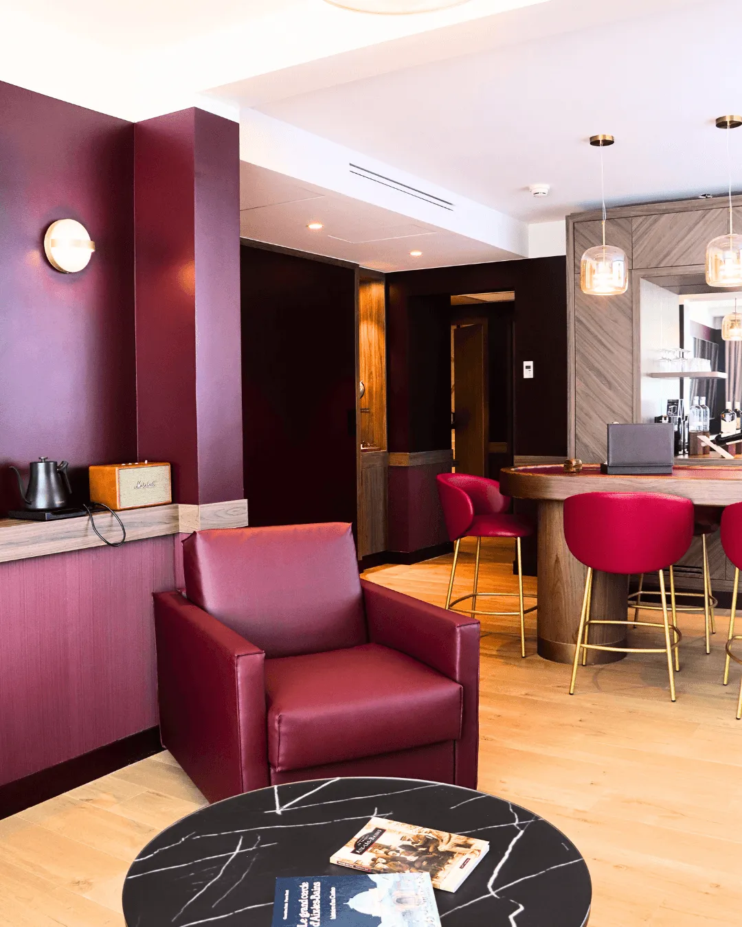 Un salon moderne avec des sièges en cuir marron, une table en marbre noir et un coin bar avec des tabourets assortis