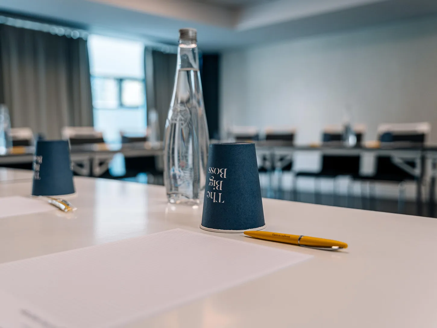 Une bouteille d'eau, un gobelet et un stylo sur une table dans une salle de réunion