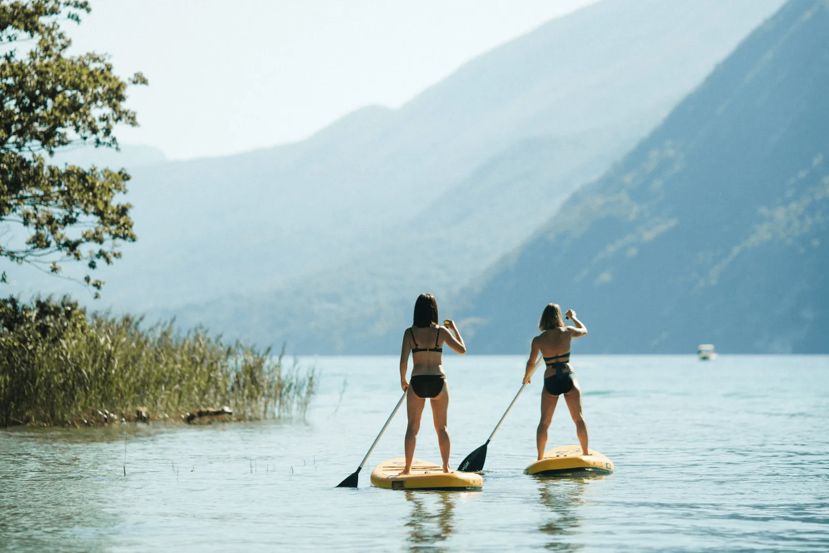 Deux personnes font du paddle sur une étendue d'eau avec des montagnes en arrière-plan