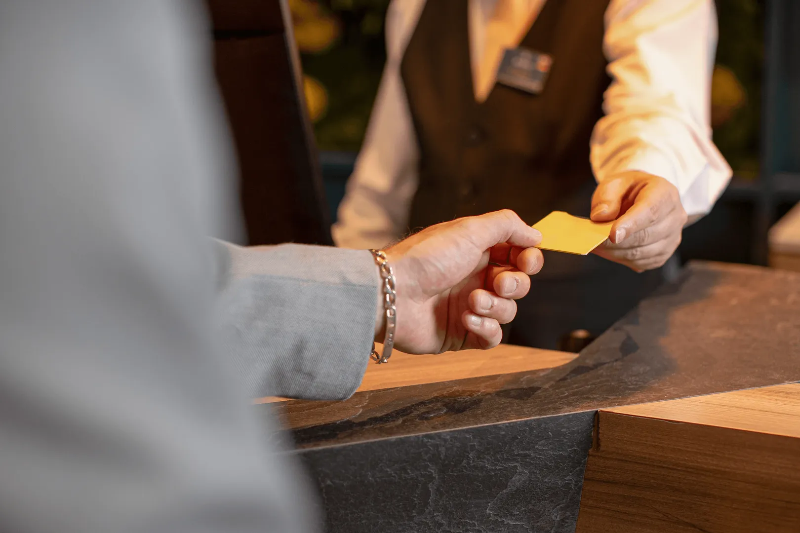 Une personne tend une carte jaune à un employé derrière un comptoir en bois