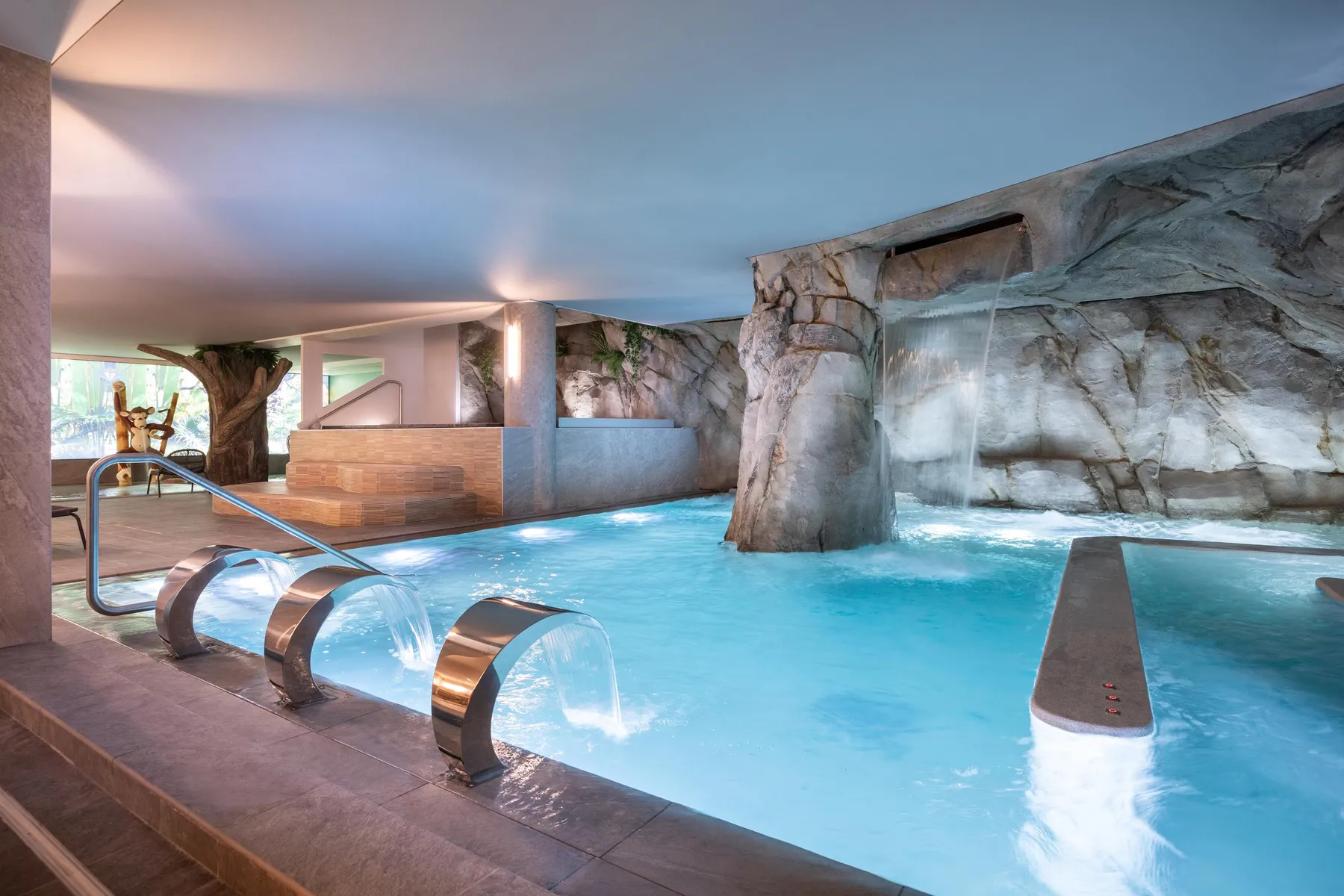 Piscine intérieure avec cascades et rochers artificiels, éclairée par une lumière naturelle tamisée