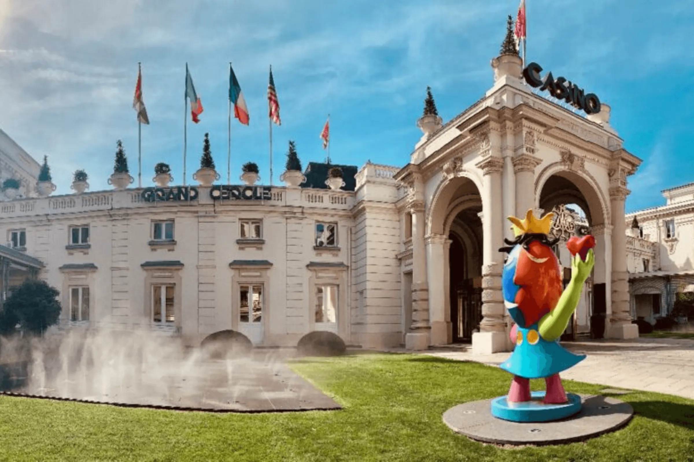 Statue colorée devant un bâtiment de style classique avec des drapeaux et l'enseigne "Casino"