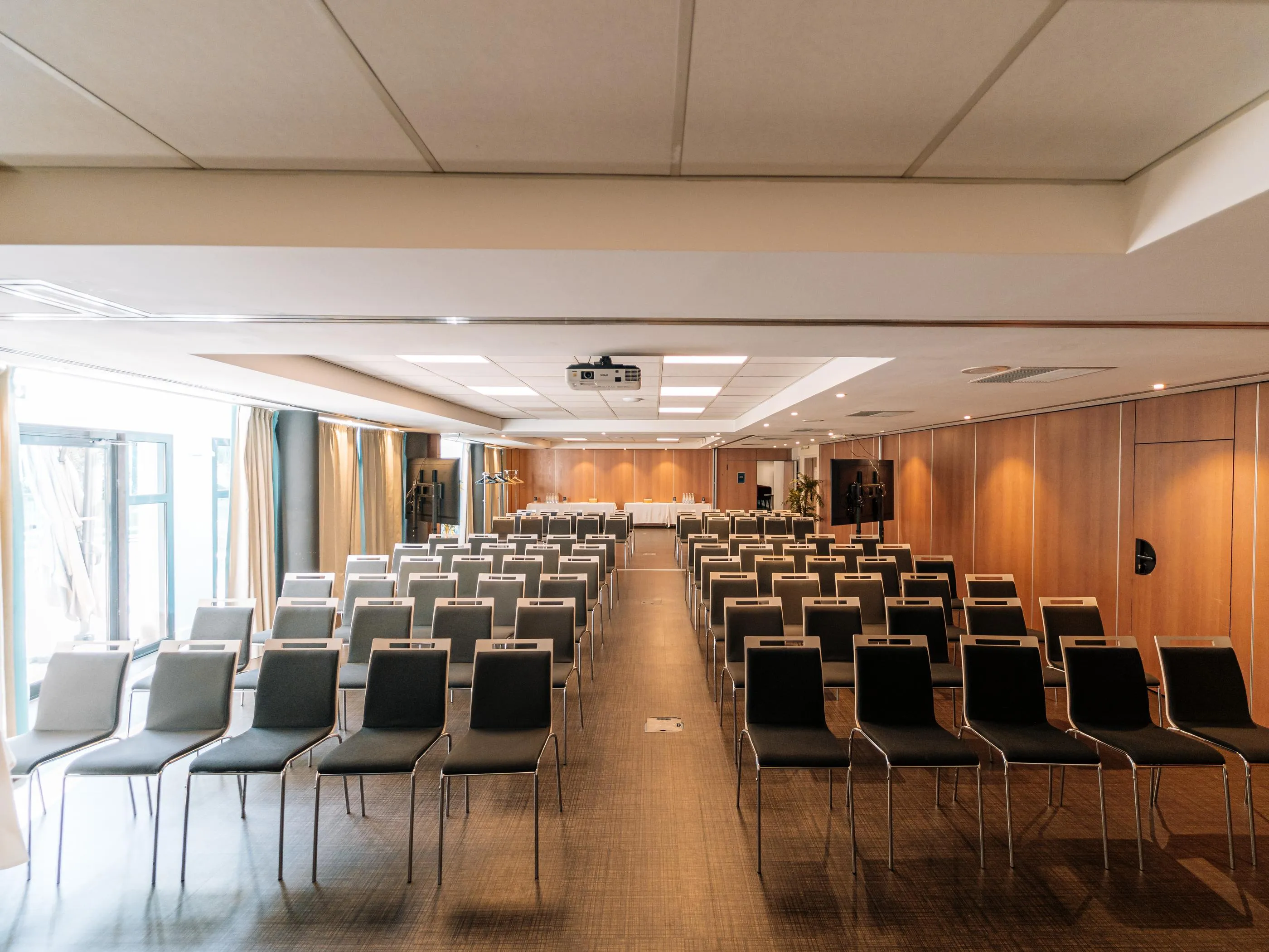 Salle de conférence avec des rangées de chaises alignées et un projecteur au plafond
