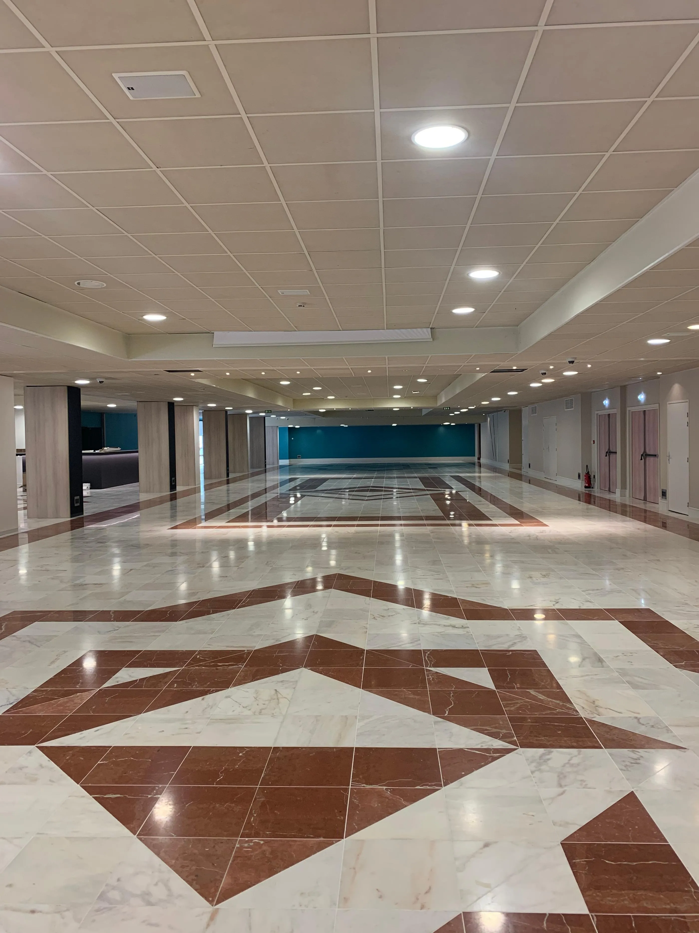 Grand hall d'intérieur avec sol en marbre à motifs géométriques et plafond à dalles lumineuses