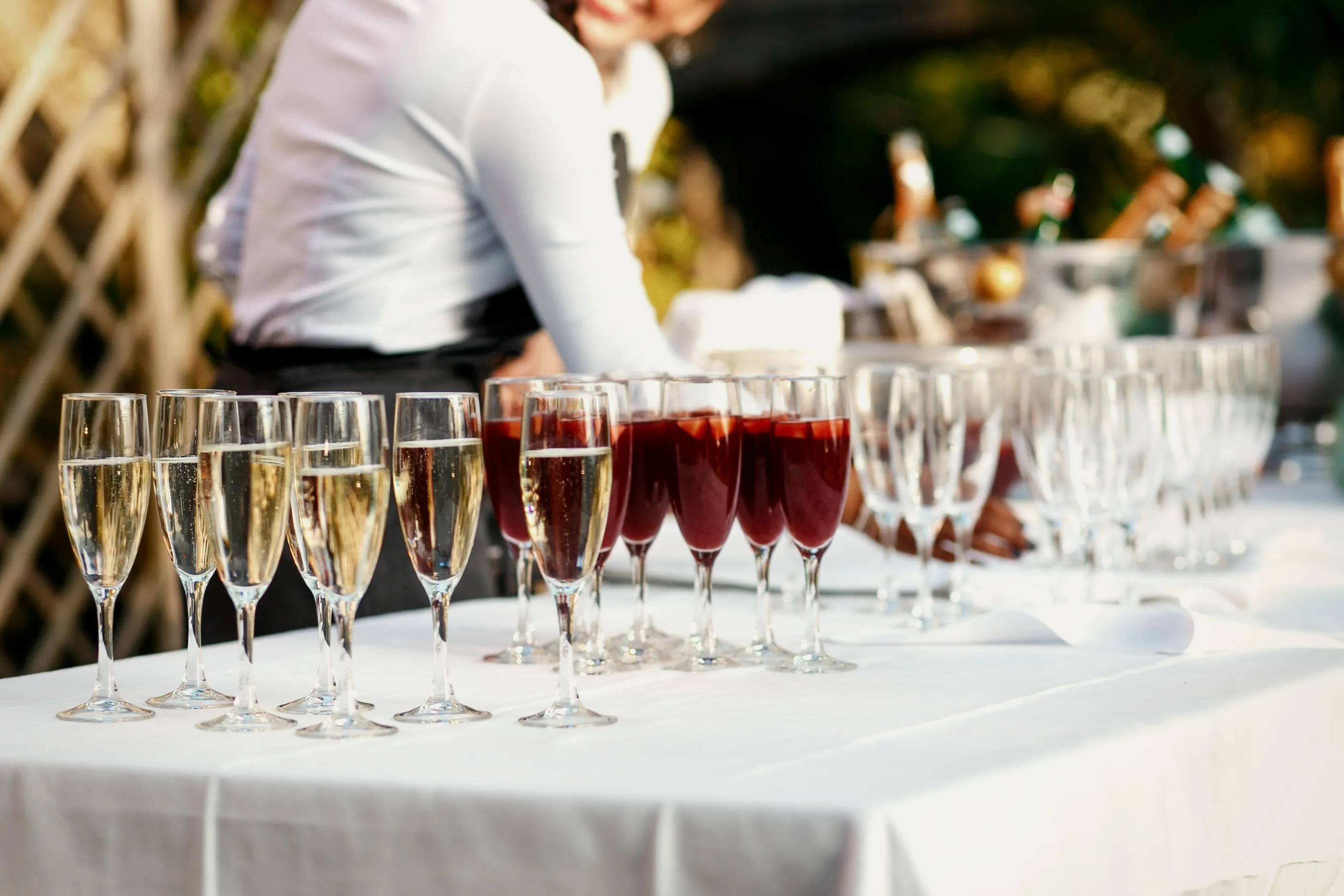 Une table avec des verres à vin contenant du vin blanc et du vin rouge, un serveur en arrière-plan