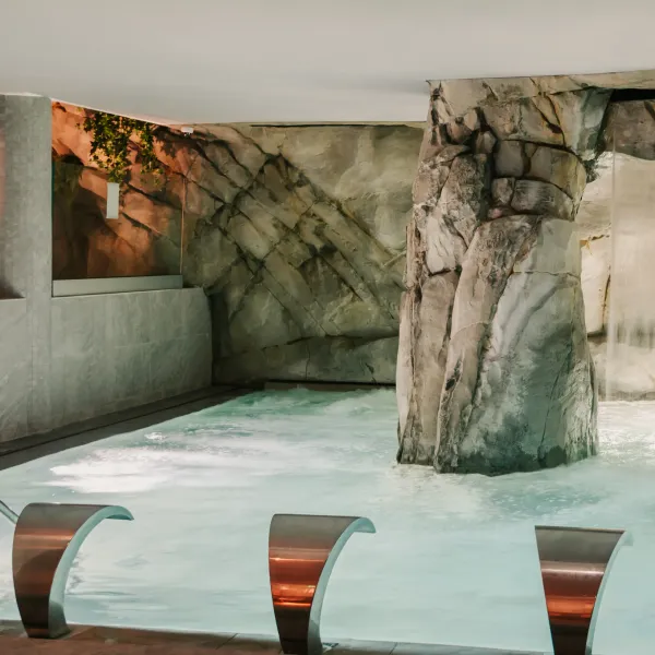 Piscine intérieure avec des rochers décoratifs et des sièges en métal partiellement immergés
