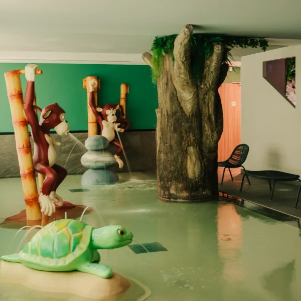 Piscine intérieure avec des sculptures de singes et de tortue, des bambous et des rochers décoratifs