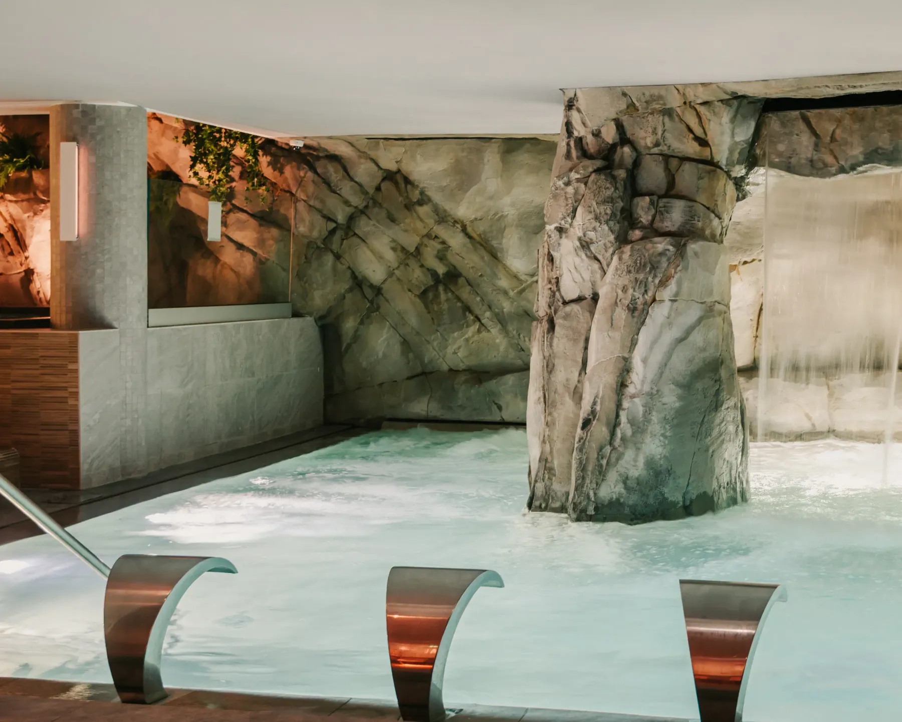 Piscine intérieure avec des rochers décoratifs et des sièges en métal partiellement immergés