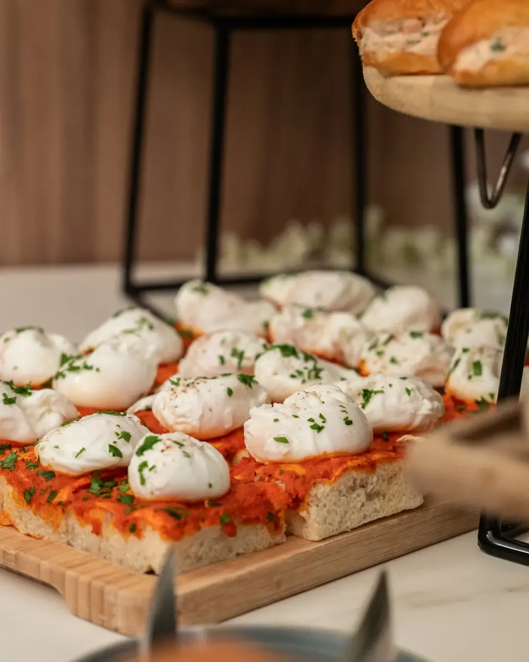 Des tranches de pain garnies de sauce tomate, de poivrons pochés et de persil, disposées sur un plateau en bois