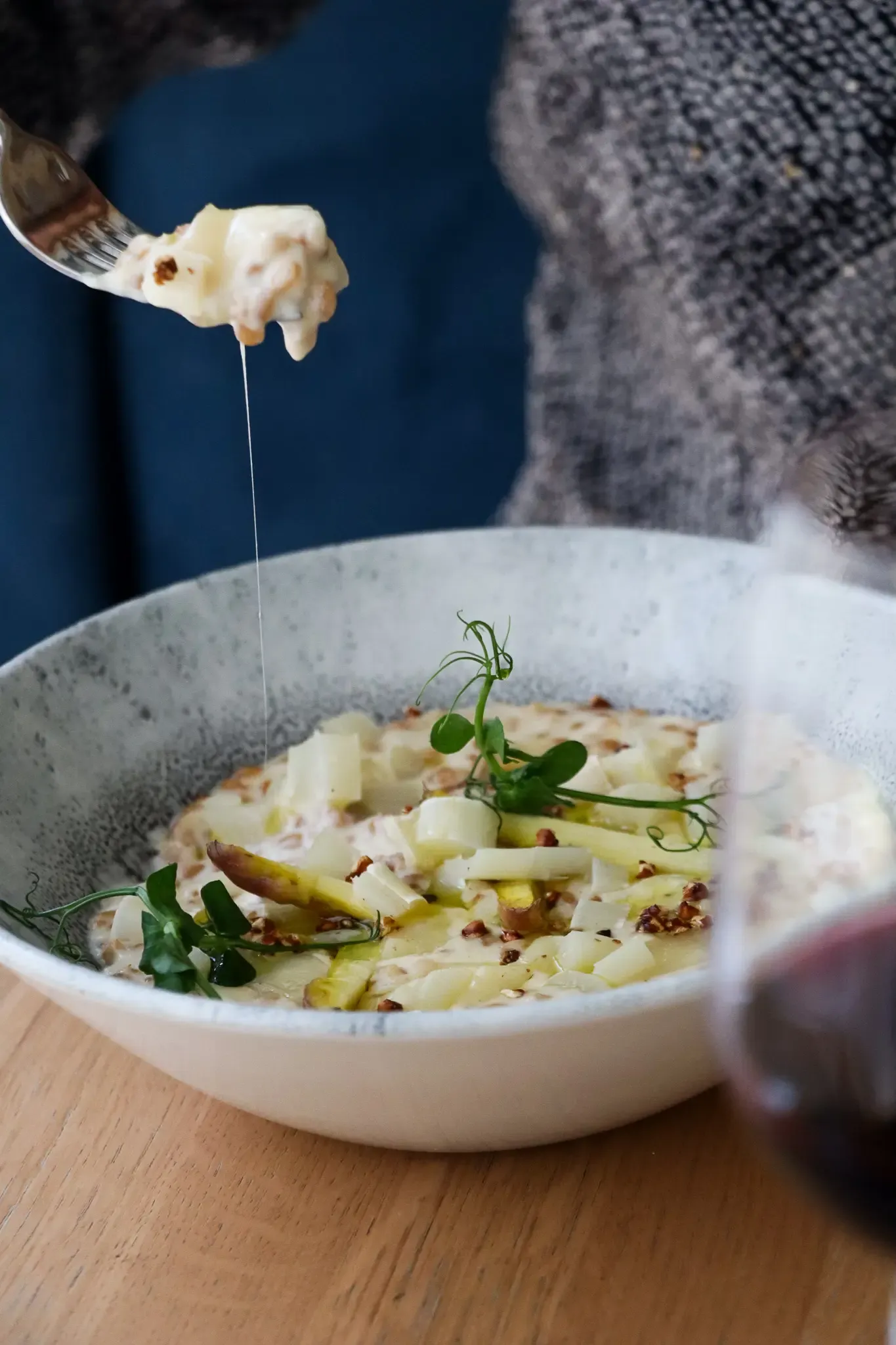 Une personne tient une fourchette avec une bouchée de gratin de pommes de terre garnie de micro-pousses