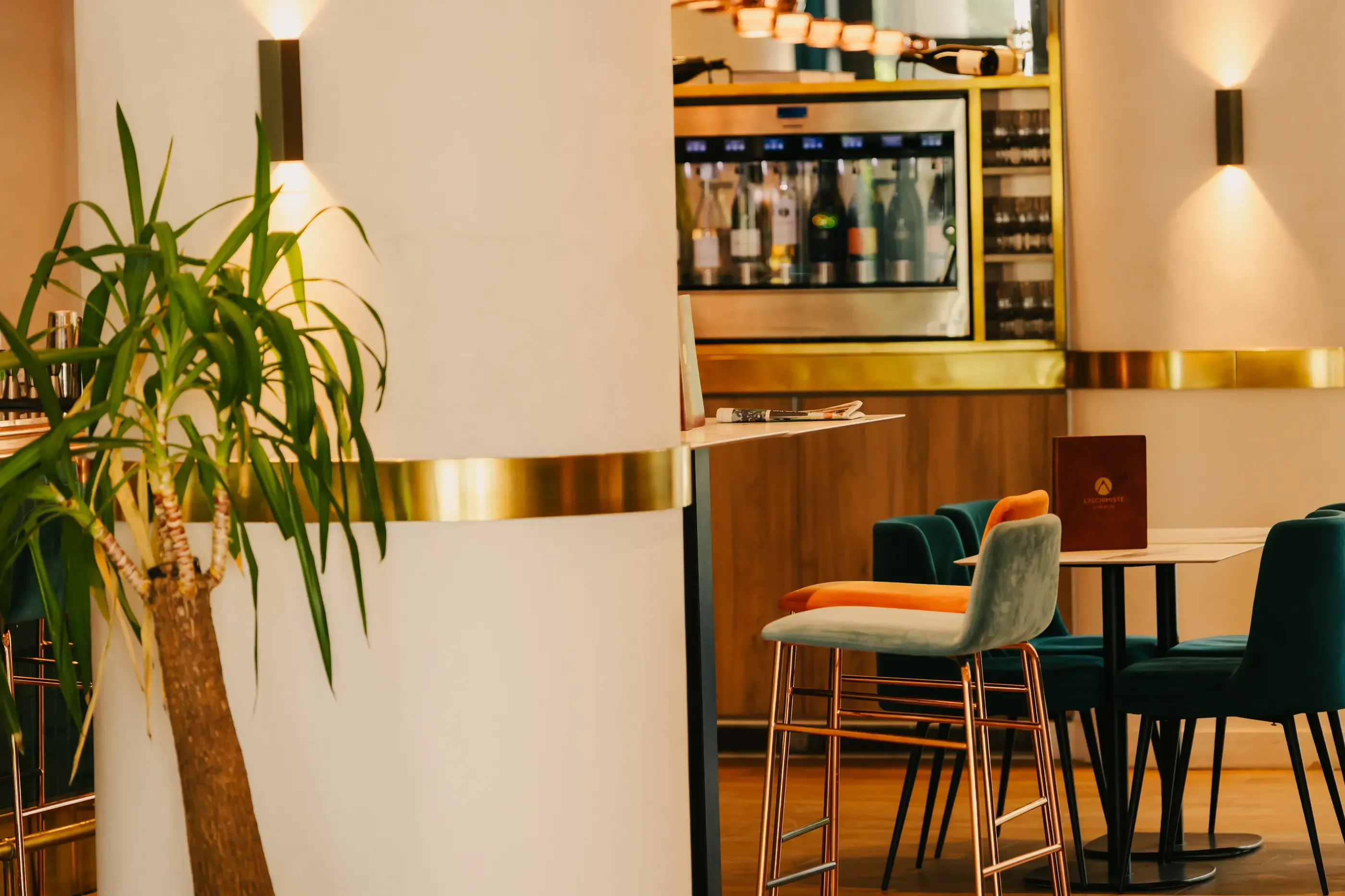 Un intérieur de restaurant avec des tables, des chaises et un bar visible en arrière-plan, éclairé par des lumières murales